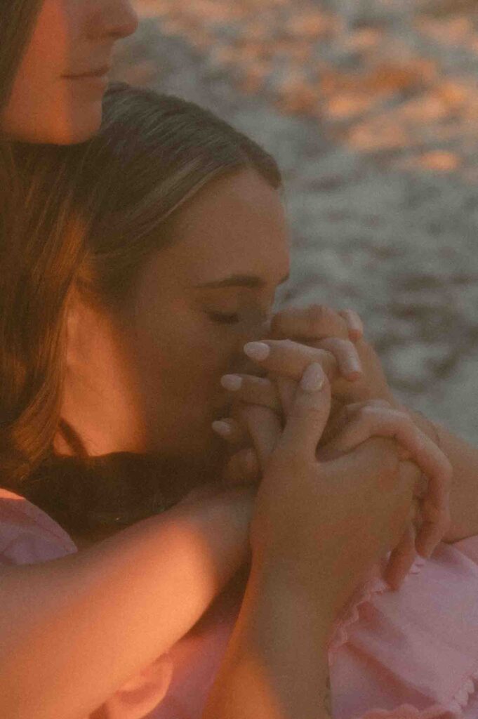 Bride kissing her partner's hands during their engagement session at Fontainebleau State Park.