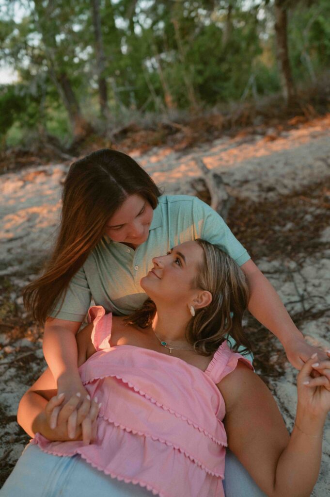 Couple sitting on log looking at each other during their engagement session at Fontainebleau State Park.