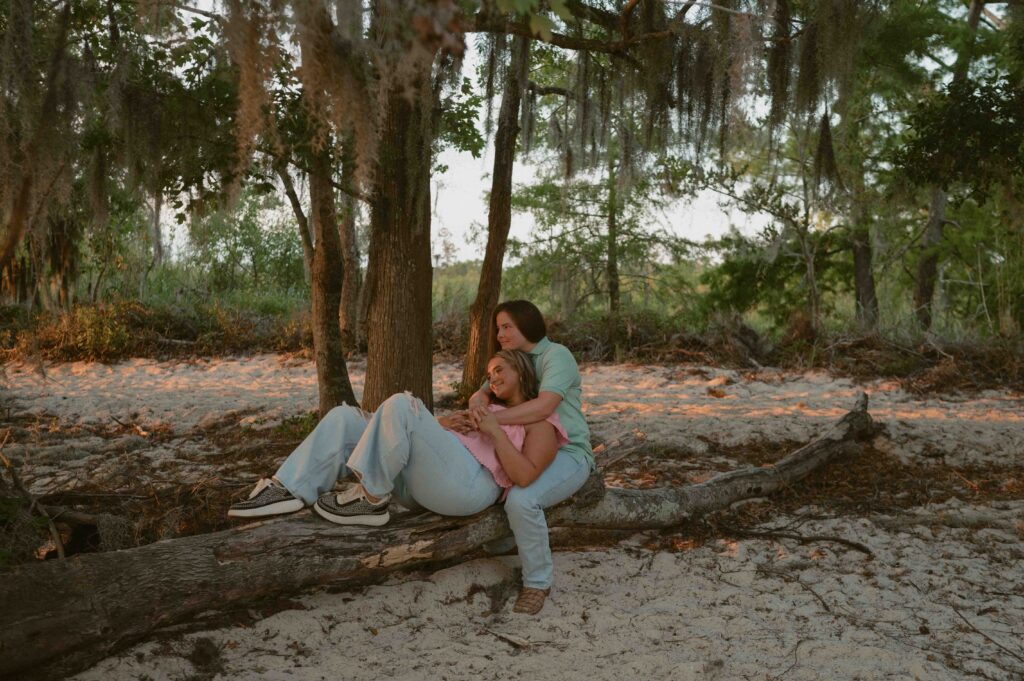 Couple sitting on log looking at the sunset during their engagement session at Fontainebleau State Park in Mandeville, LA.