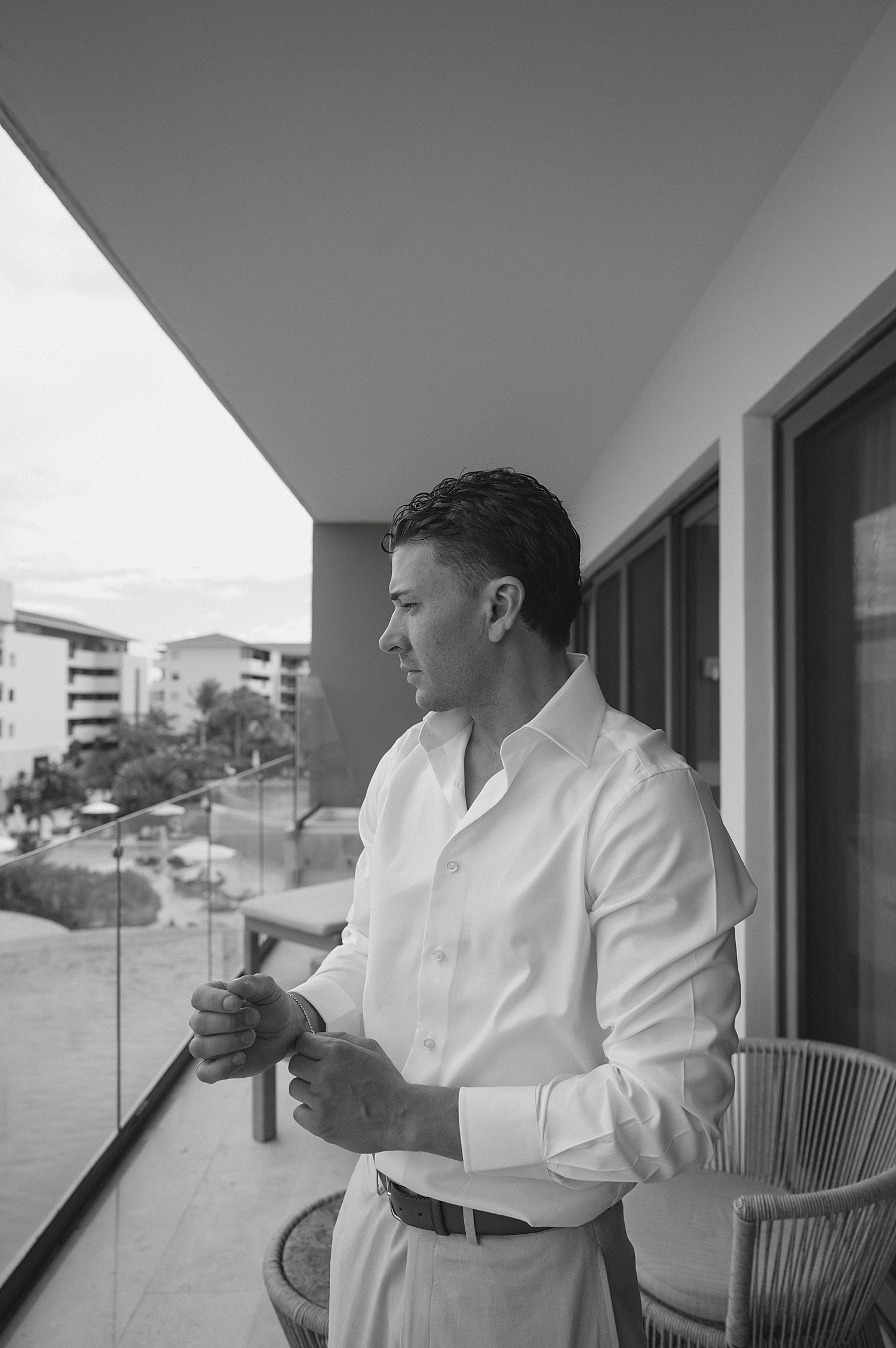 groom adjusts cuff links on balcony at Dreams Playa Mujeres