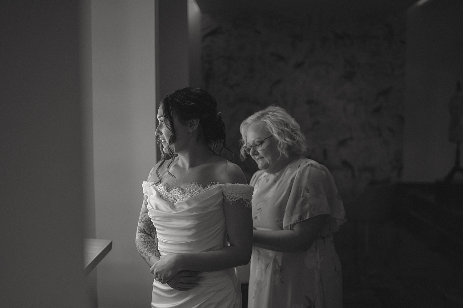 grandmother zips up bride's dress in getting ready room by Thistle and Veil Photo