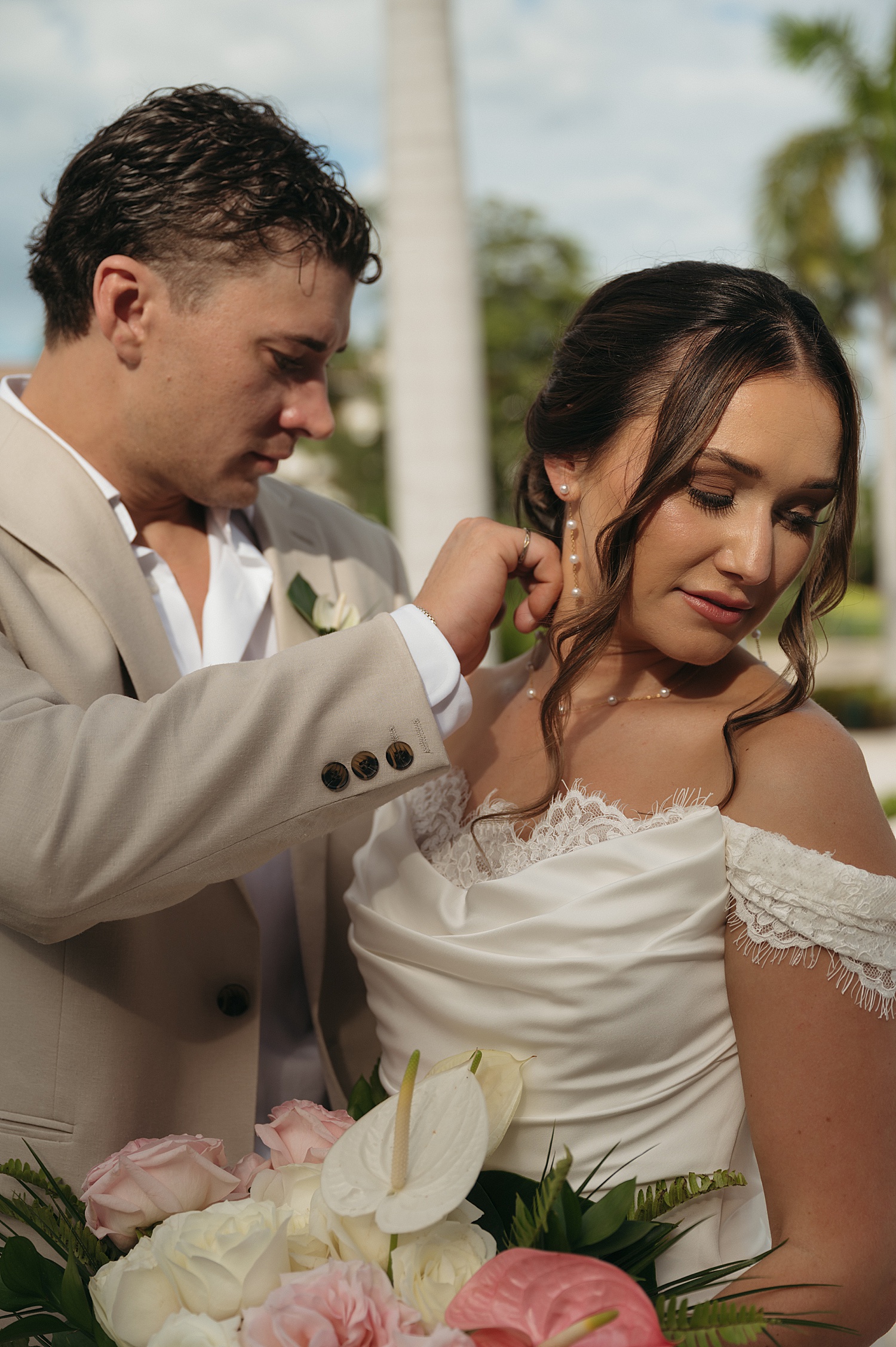 groom adjusts bride's necklace outside at Dreams Playa Mujeres