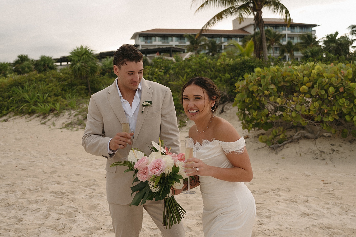 newlyweds giggle together while holding champagne by Thistle and Veil Photo