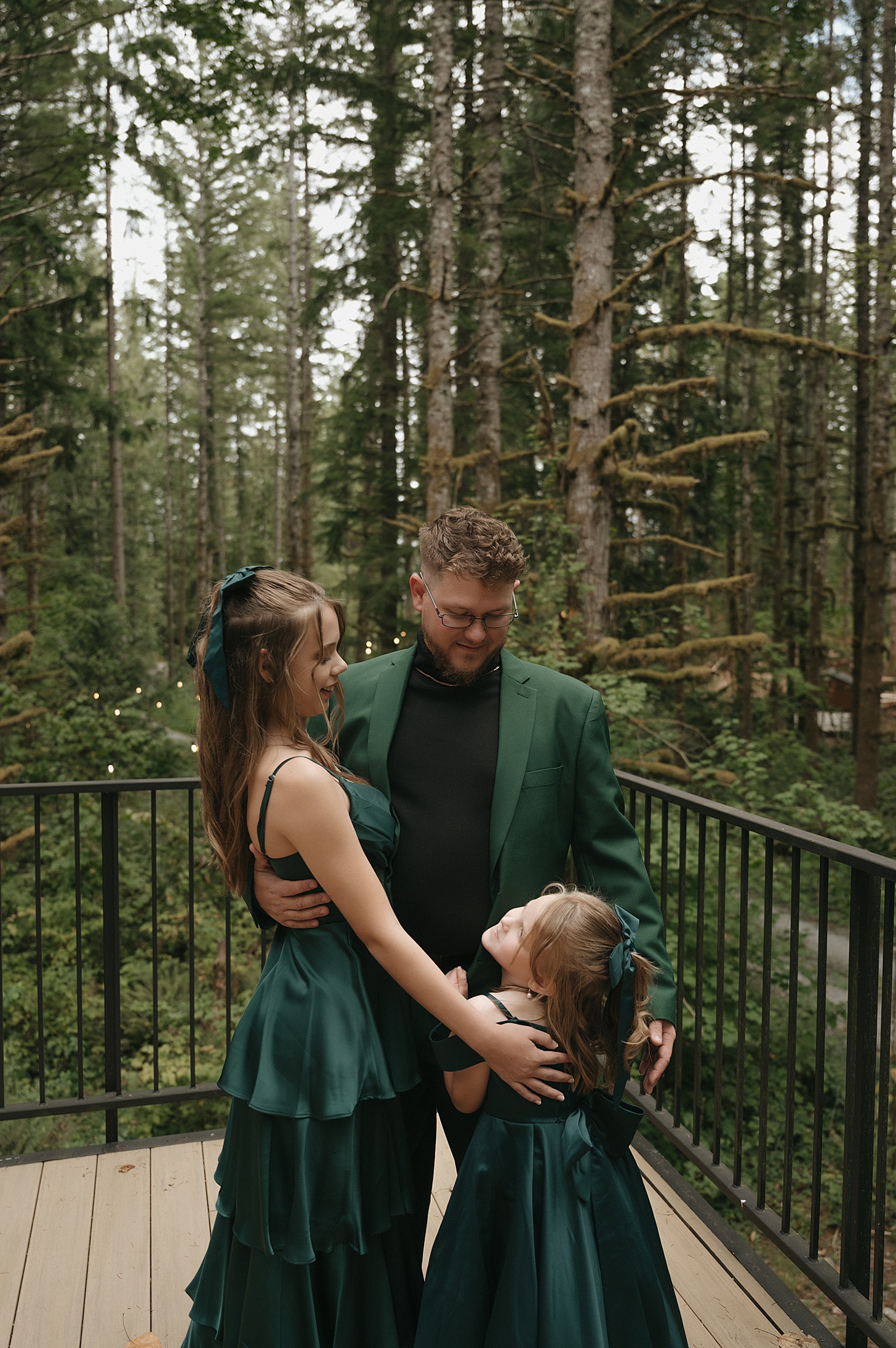 dad in green suit hugs his two daughters in matching outfits by Thistle and Veil Photography
