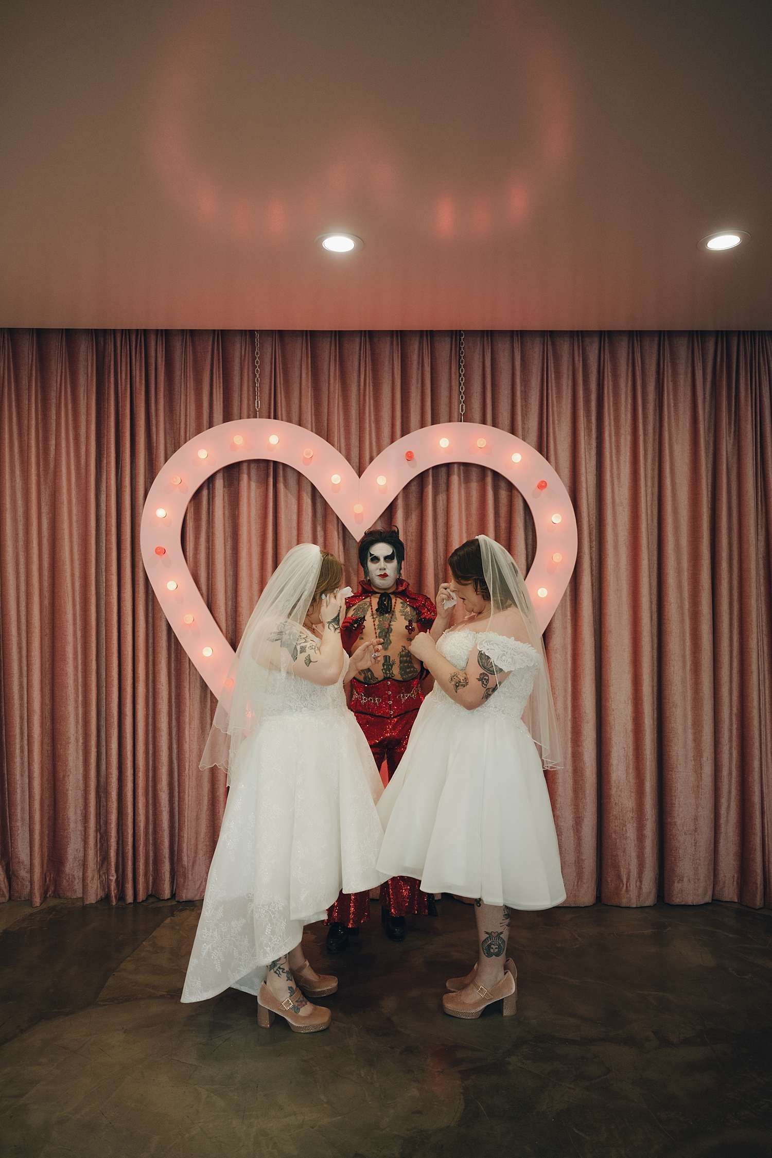 Brides both wipe their eyes at the alter with Hellvis at Sure Thing Chapel