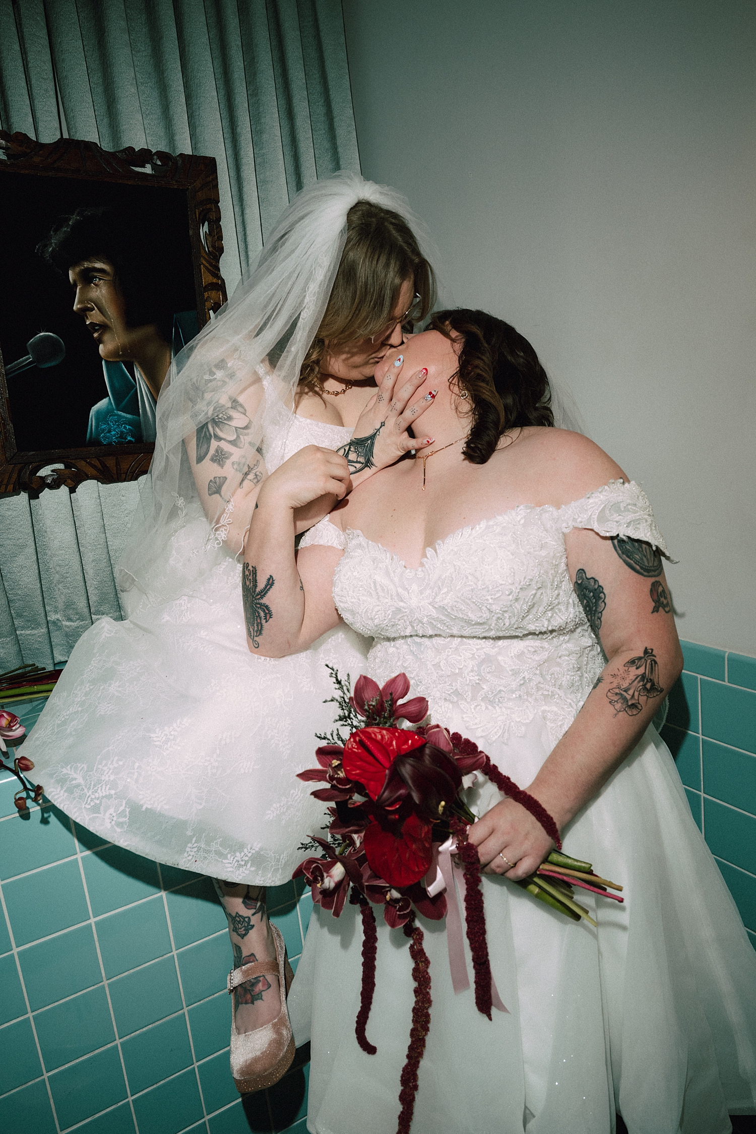 brides share a kiss in blue tile bathroom at Sure Thing Chapel