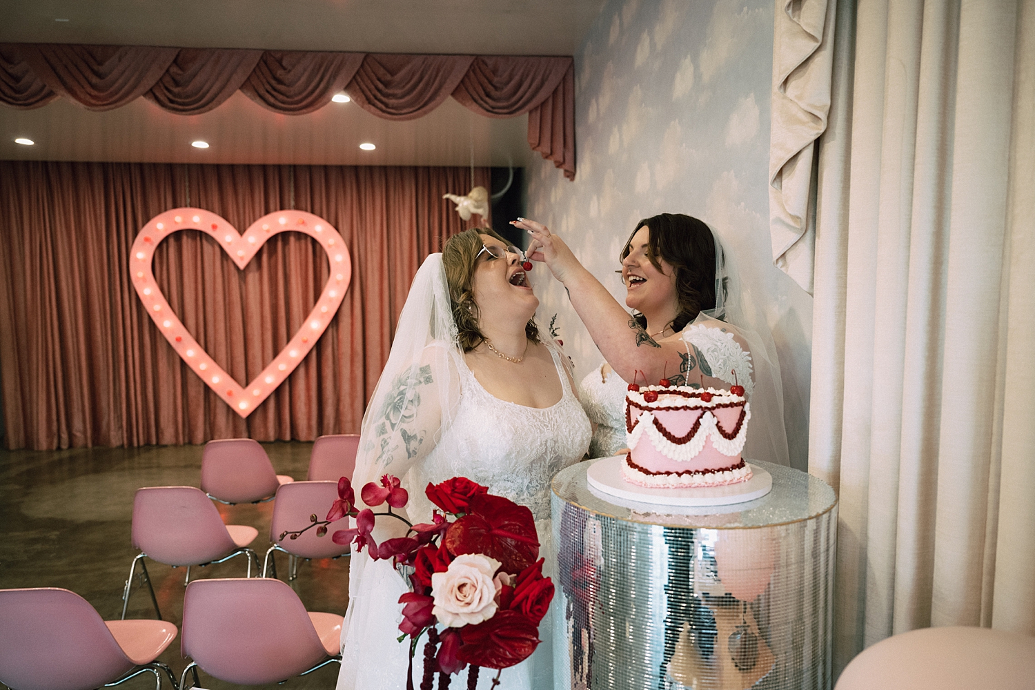 one bride feeds another bride a cherry from cake by travel elopement photographer