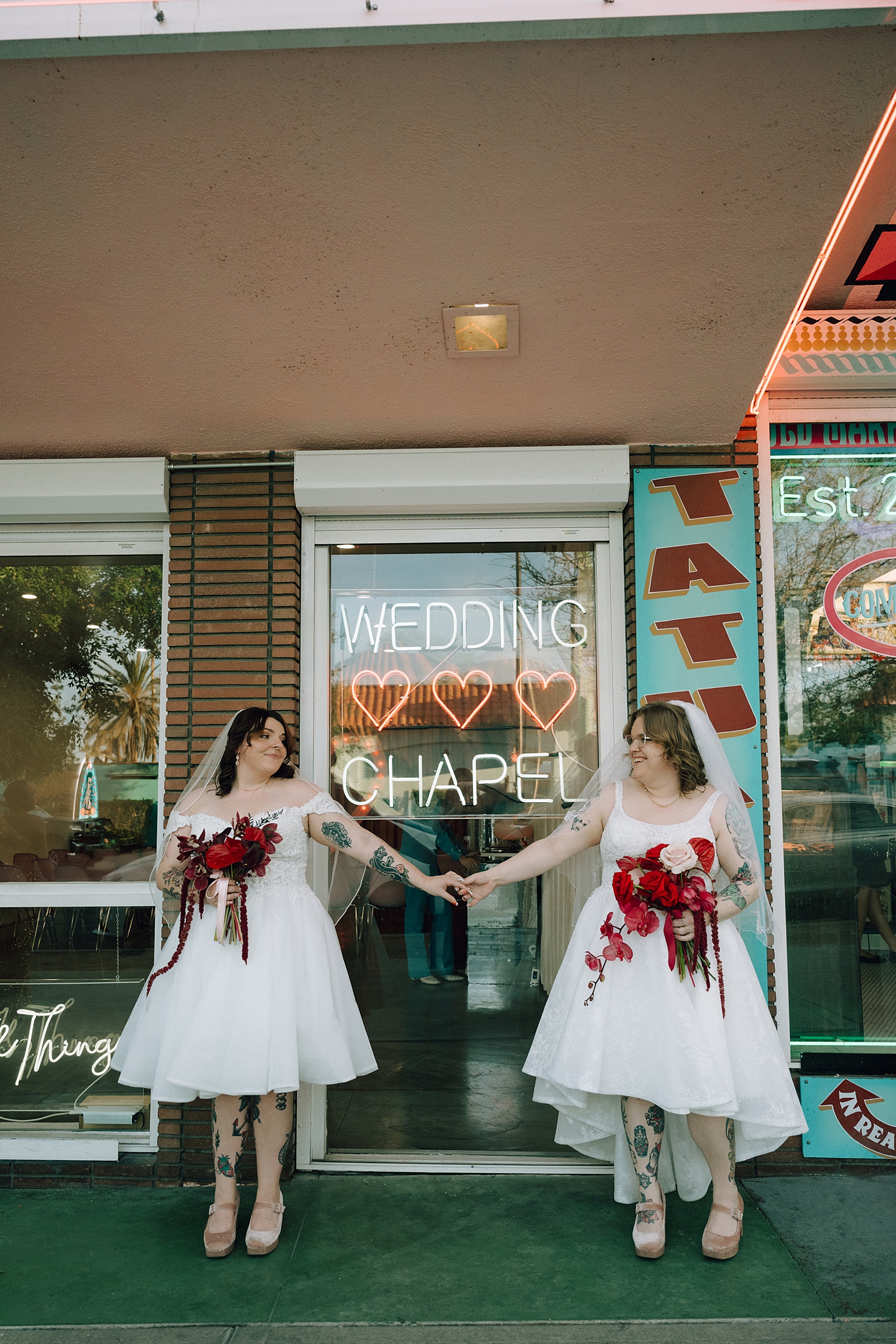 newlyweds holding hands in front of tattoo shop by Thistle and Veil Photo