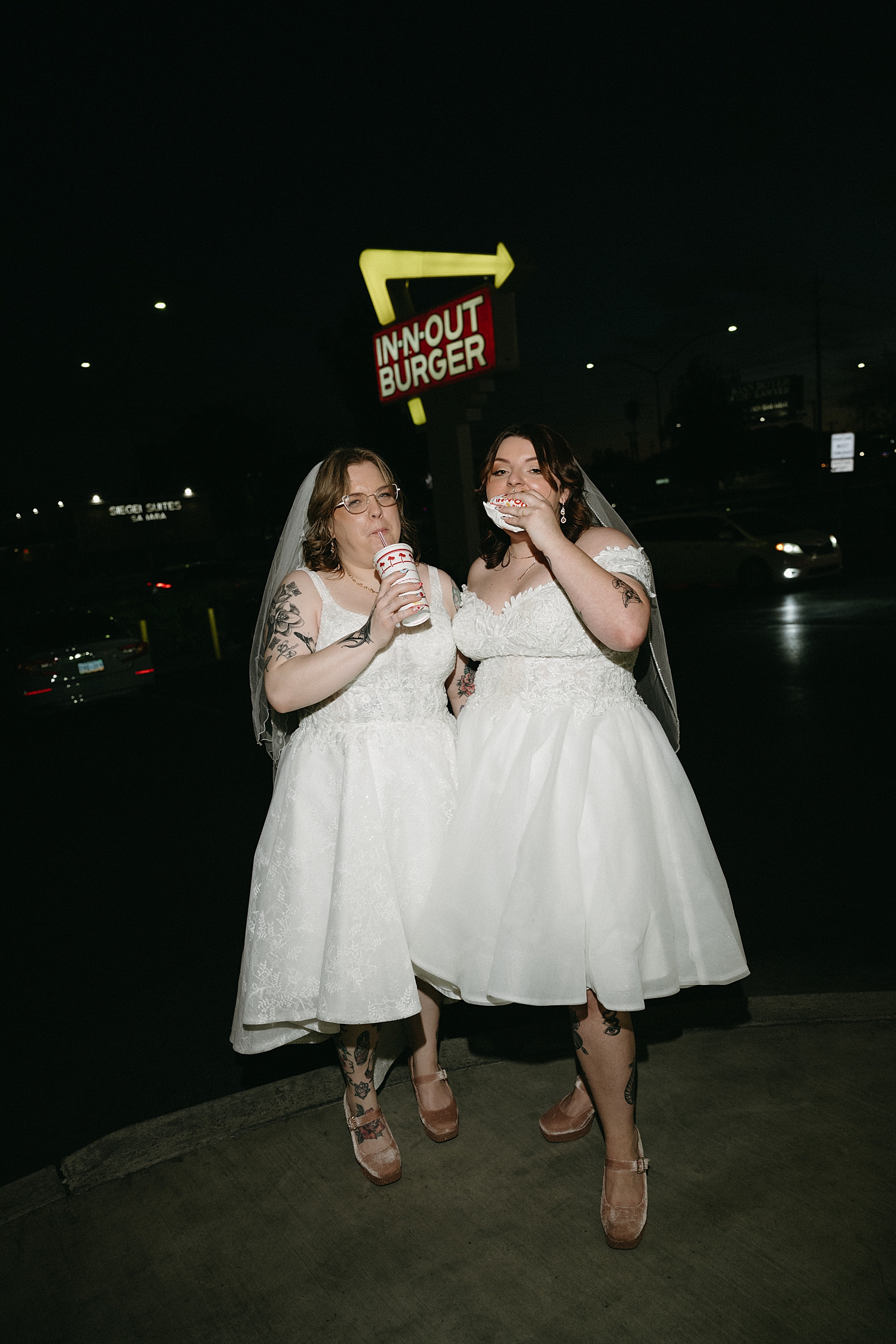 newlyweds share a burger in front of in and out sign by travel elopement photographer
