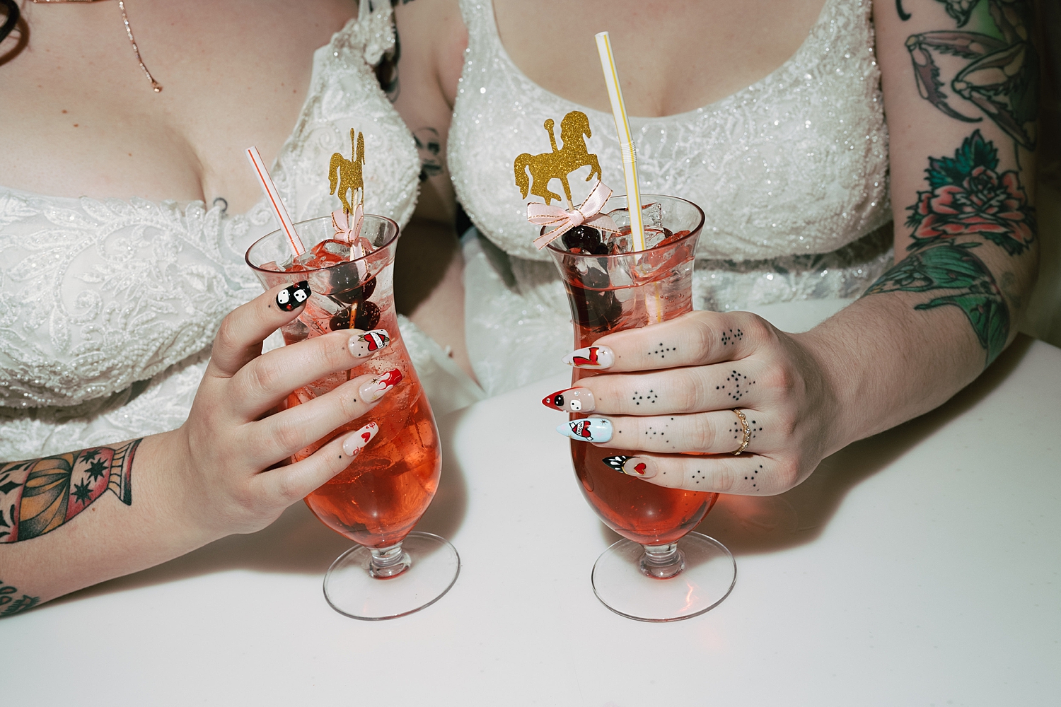 women with finger tattoos in wedding gowns share a custom cocktail by Thistle and Veil Photo