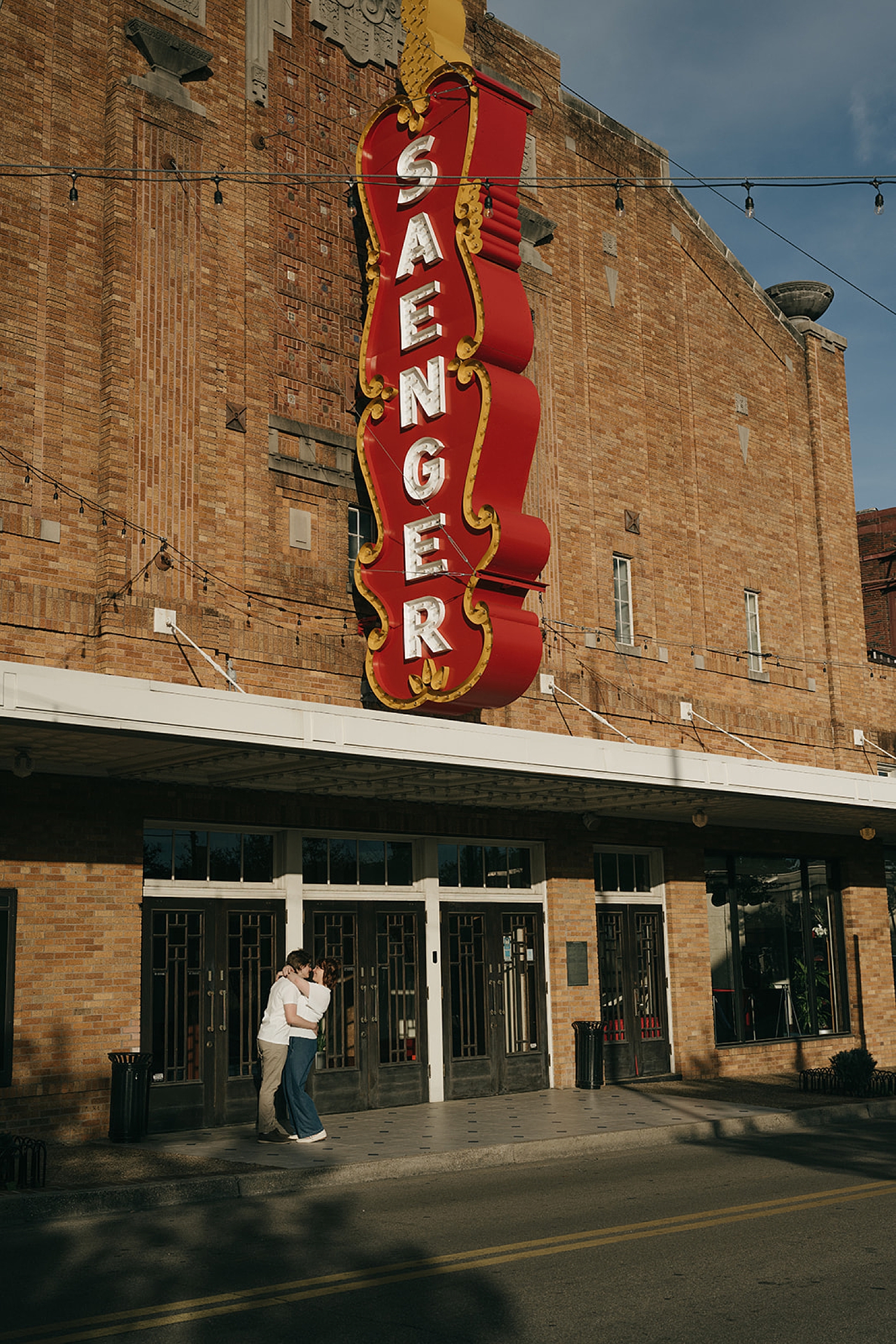 man and woman share a kiss under big street sign for non-traditional engagement photos