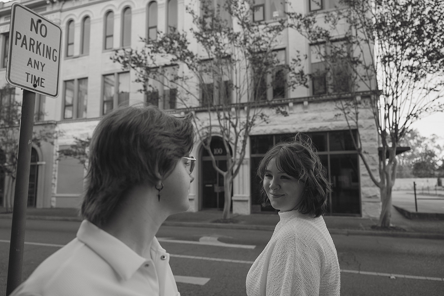 woman looks back at her fiance on street for non-traditional engagement photos