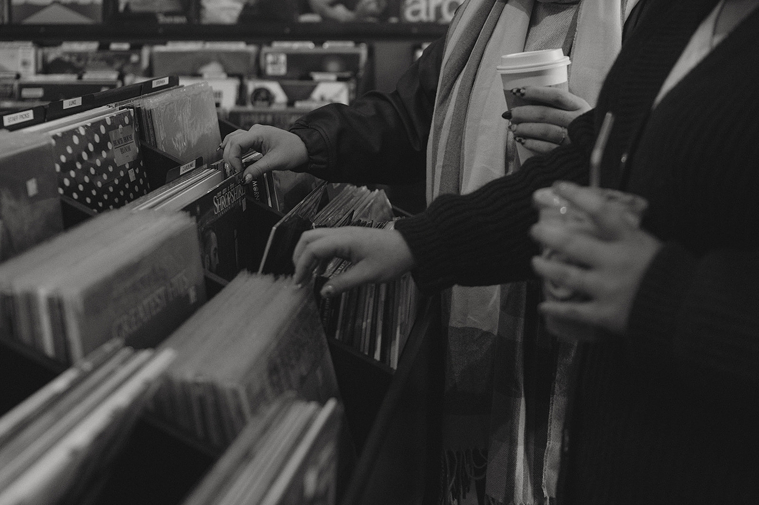 couple sift through vinyls at record store by travel elopement photographer