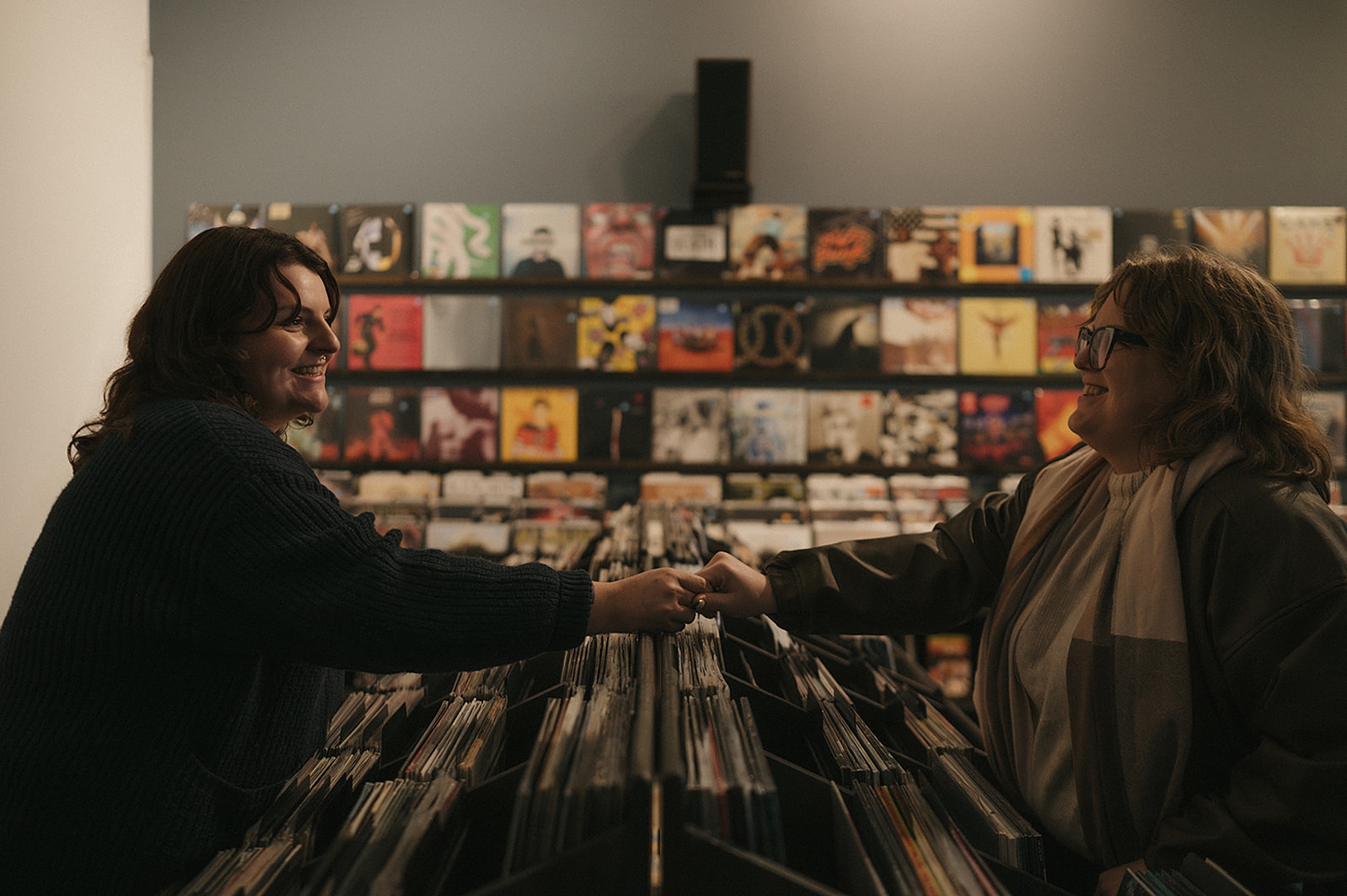 engaged couple hold hands over vinyl display by travel elopement photographer