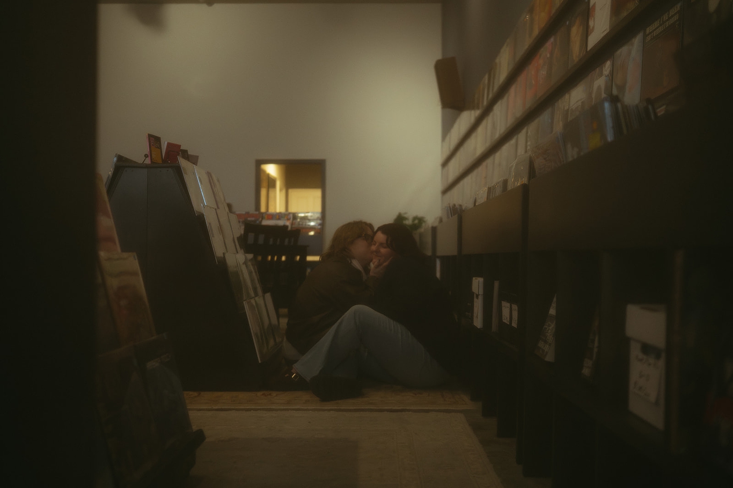 couple share a kiss sitting on the floor of record shop by travel elopement photographer