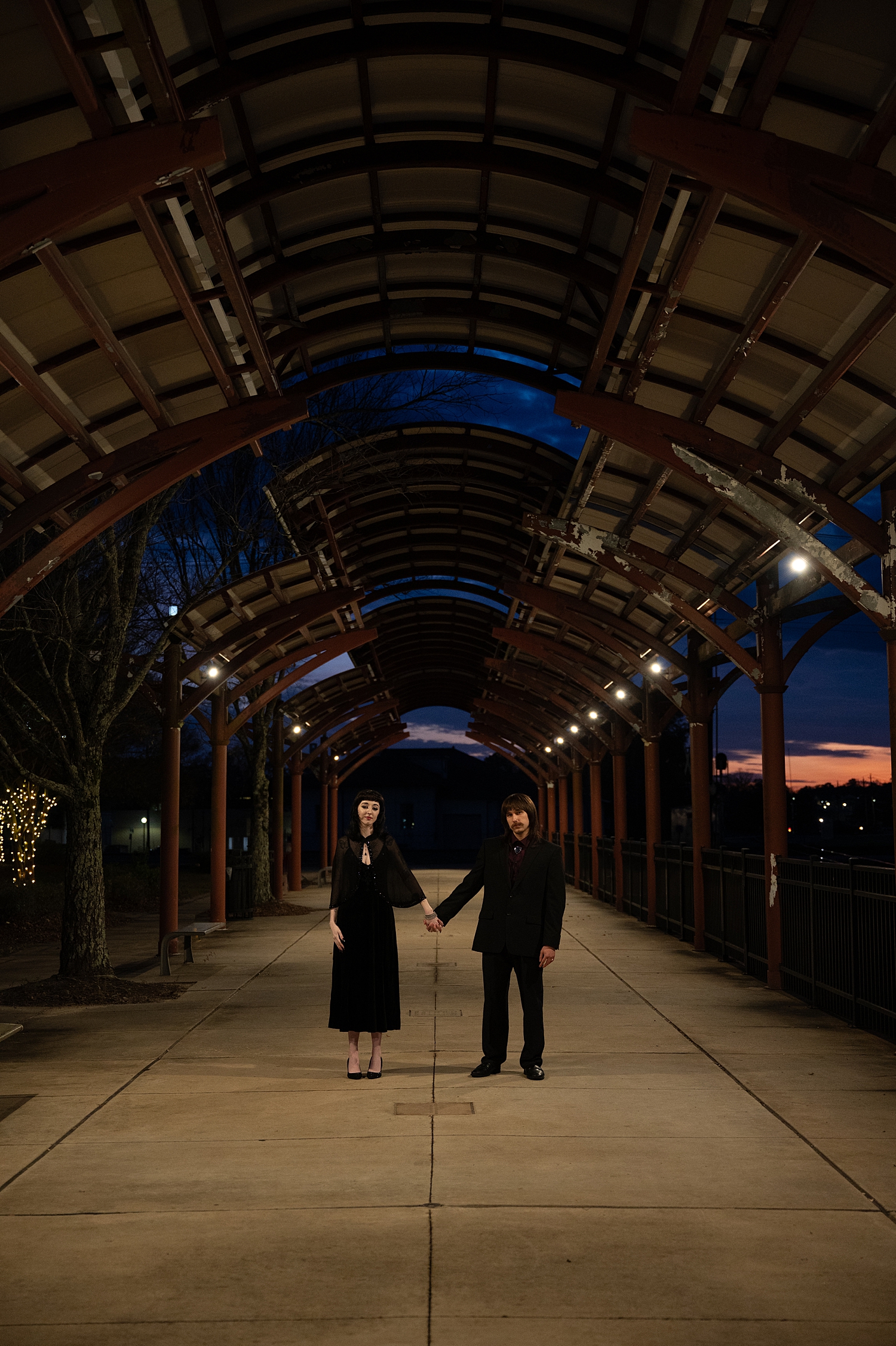 engaged couple hold hands under industrial awning by travel elopement photographer