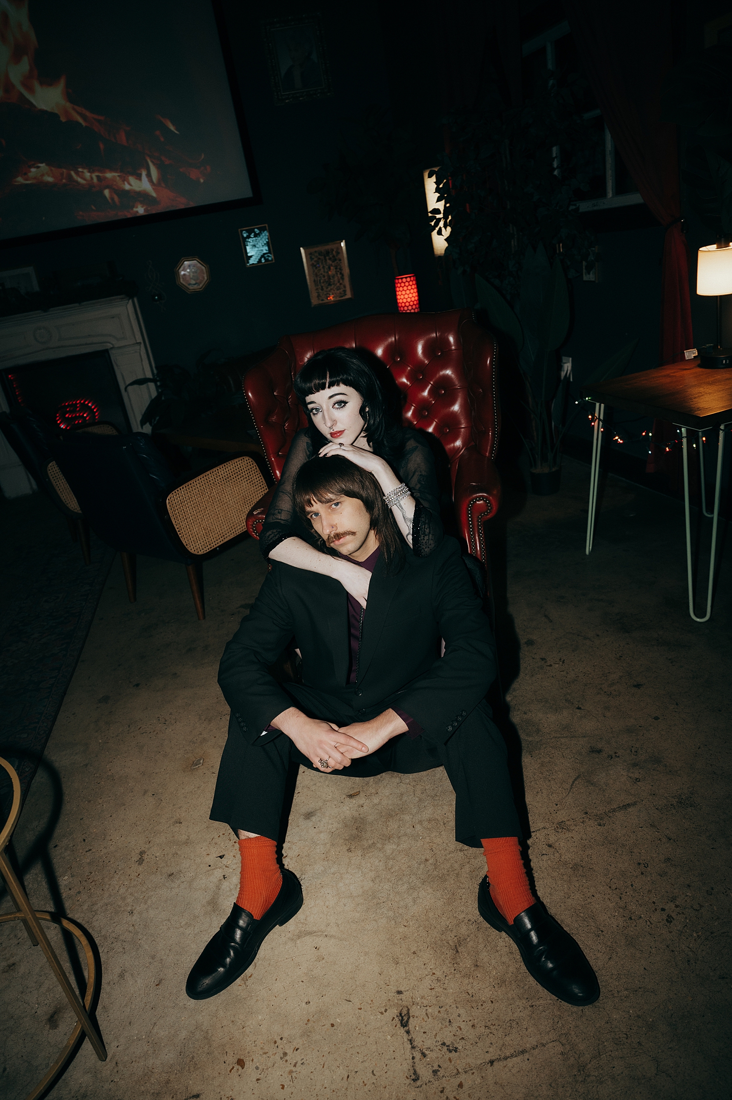 goth couple sit in warehouse in big chair by Thistle and Veil Photography