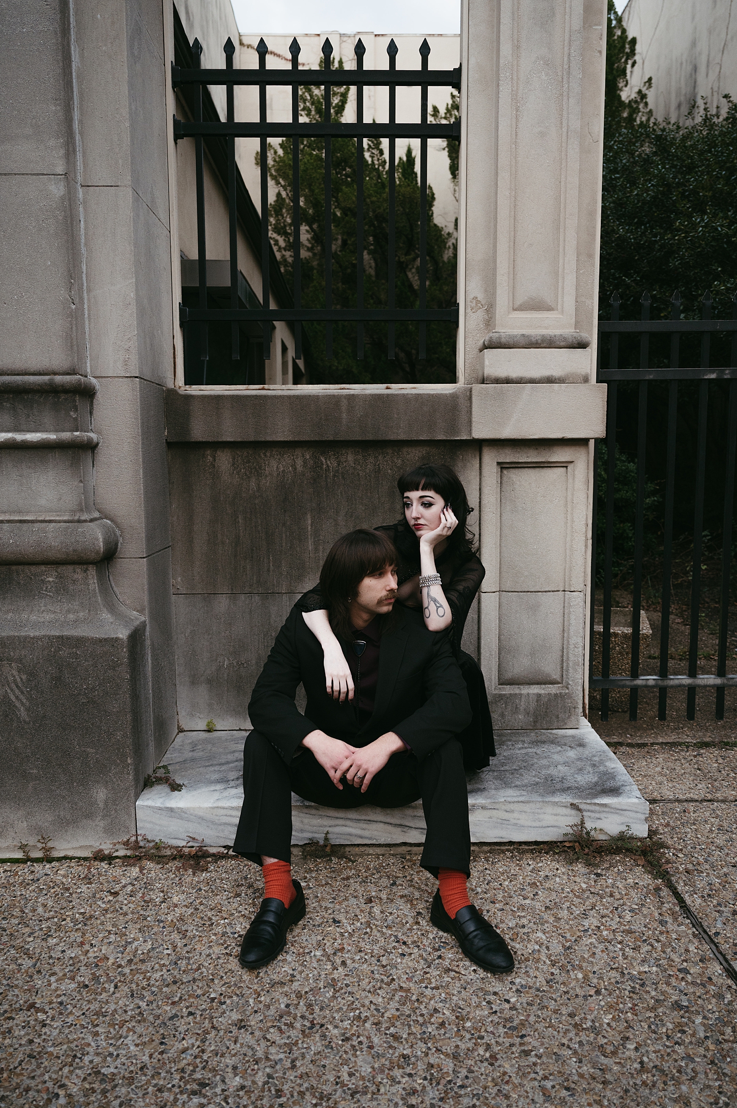 man and woman sit under large column by Thistle and Veil Photography