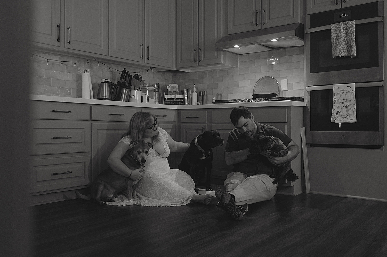 man and woman sit on kitchen floor with their pups by Thistle and Veil Photography